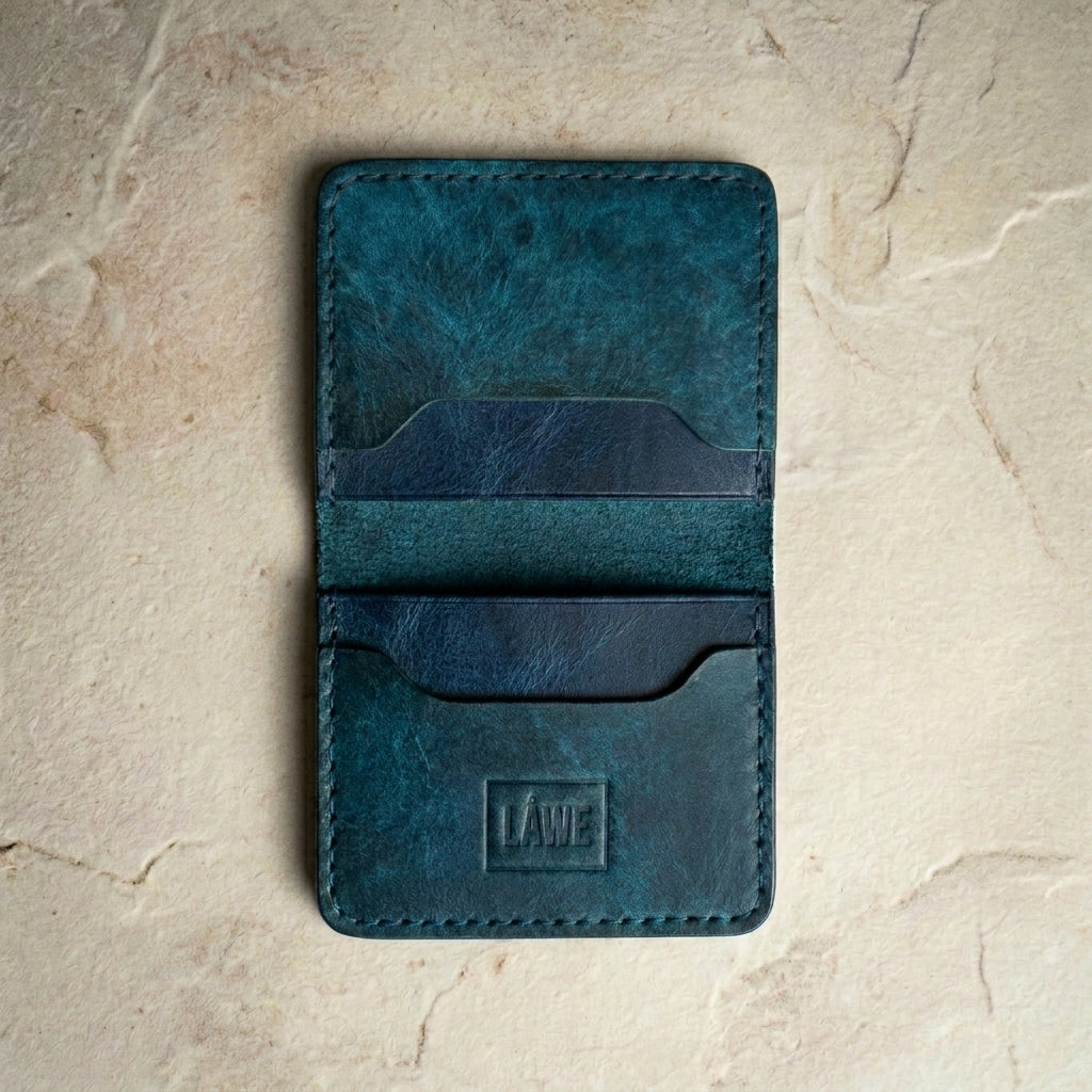 LÅWE Classic Aegean Edge - blue leather cardholder on a textured beige surface