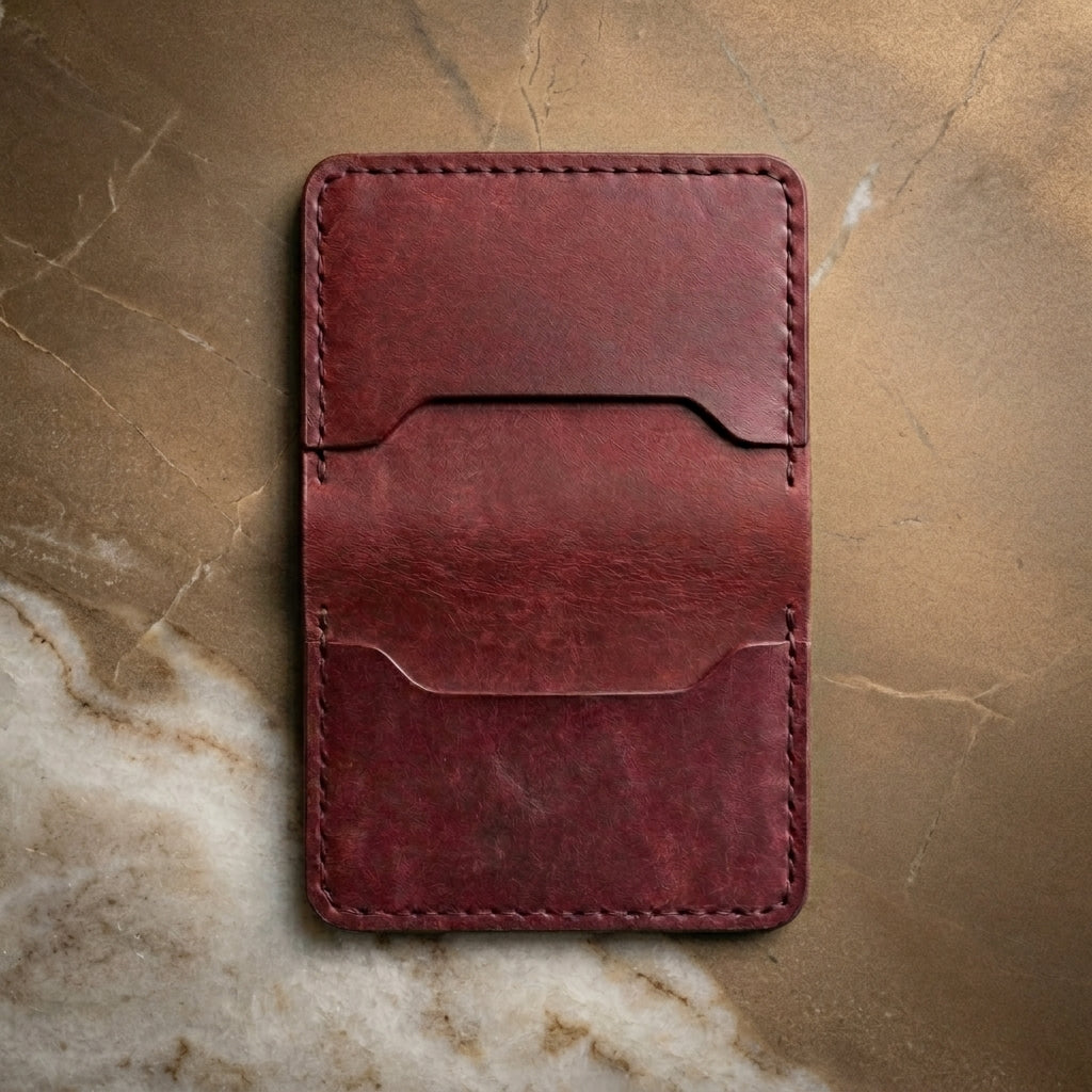 LÅWE Bordeaux Edge - burgundy leather wallet on a textured bronze surface
