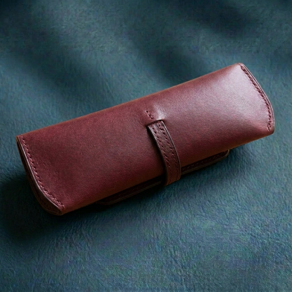 Bordeaux LÅWE Focus leather eyewear case's back on a textured slate surface