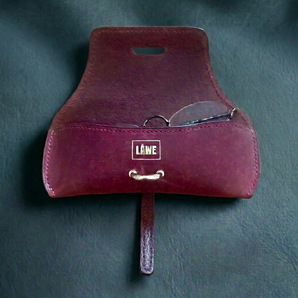 Bordeaux LÅWE Focus eyewear leather case with reading glasses inserted on a slate background