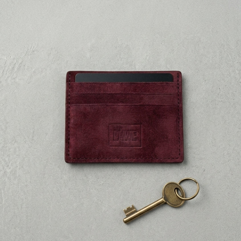 Maroon cardholder with 'LÅWE' branding on a light gray background, accompanied by a gold key.