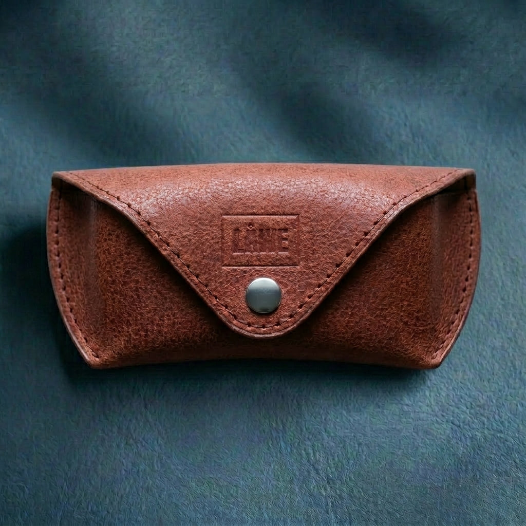 Brown leather eyewear case with a metal button on a textured grey background
