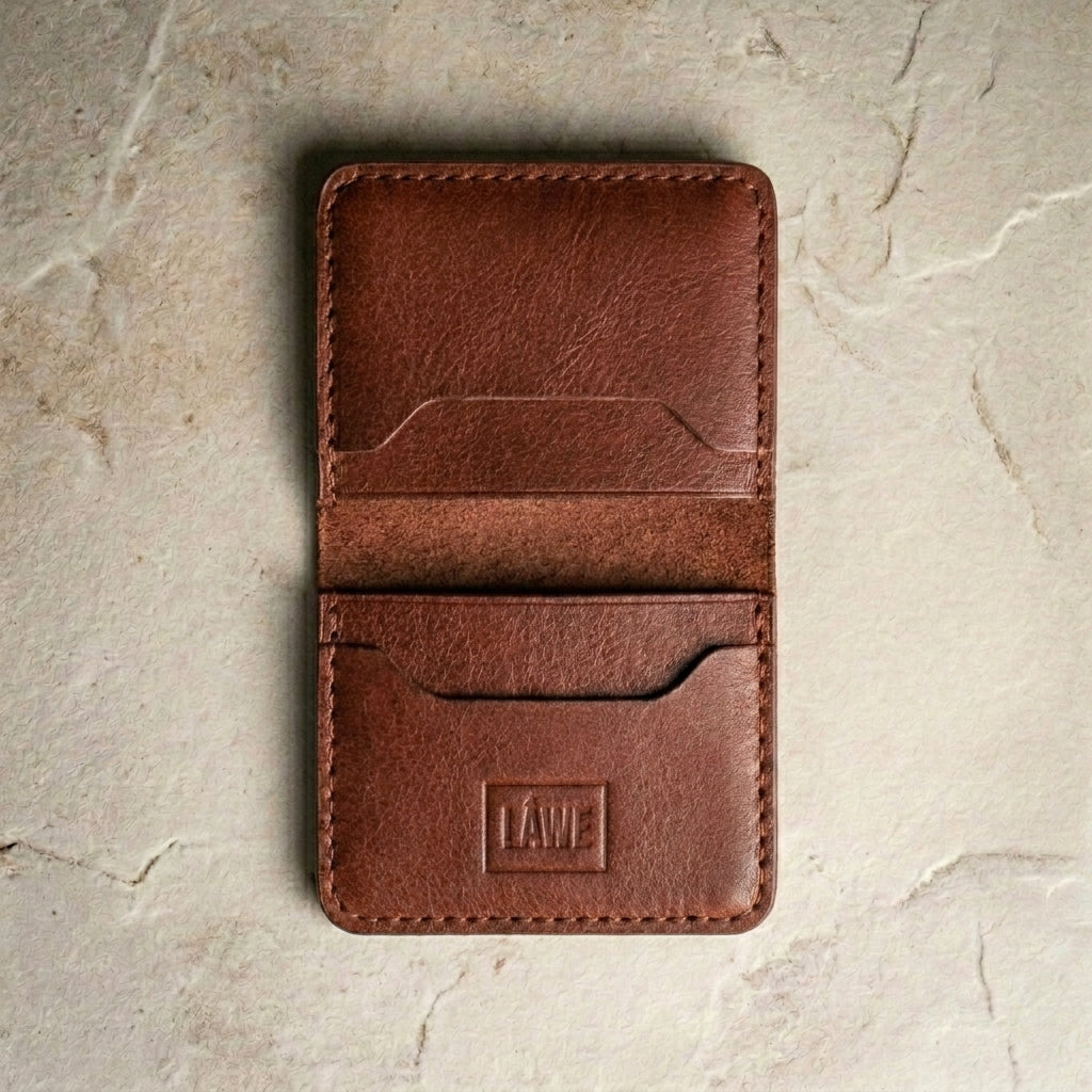Amber brown leather wallet with 'LÅWE' branding on a beige stone surface