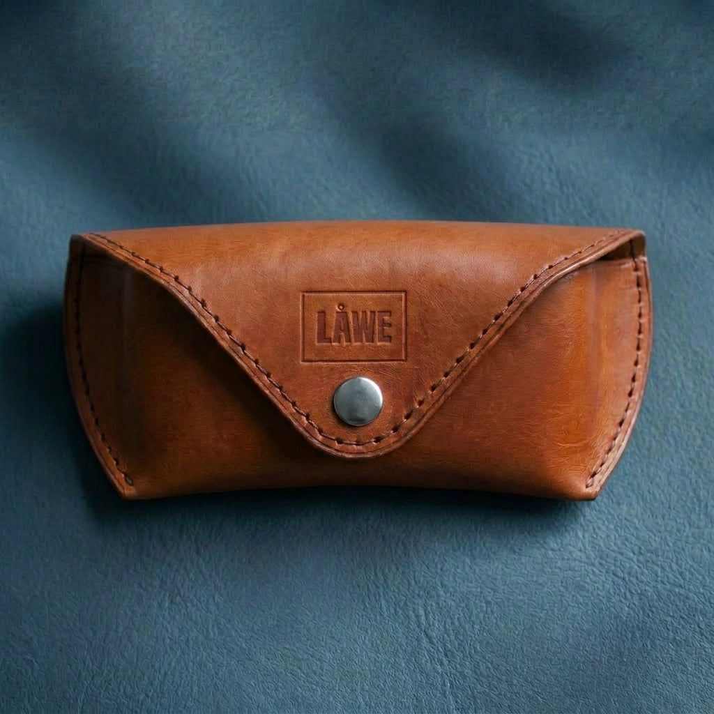 Brown leather eyewear case with a metal button on a blue background
