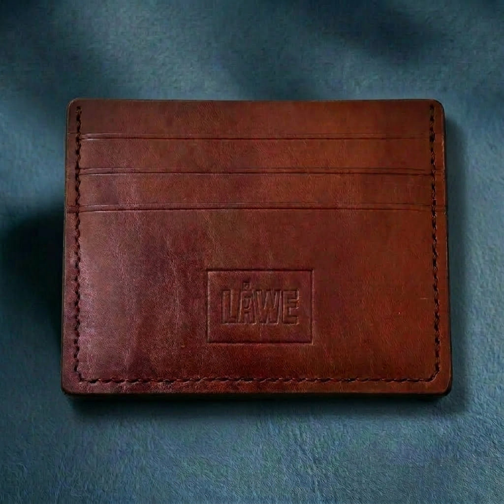 Brown leather wallet with 'LÅWE' branding on a blue textured background