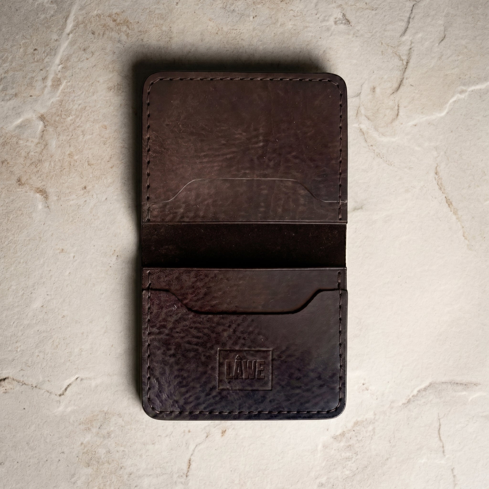 LÅWE Espresso Classic Edge - brown leather wallet with a visible brand logo on a light stone surface