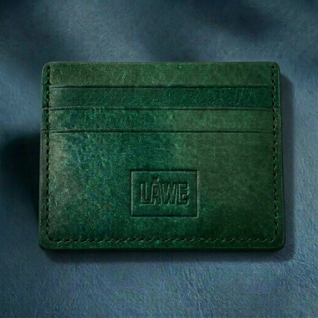 Green leather cardholder with 'LÅWE' branding on a dark blue background