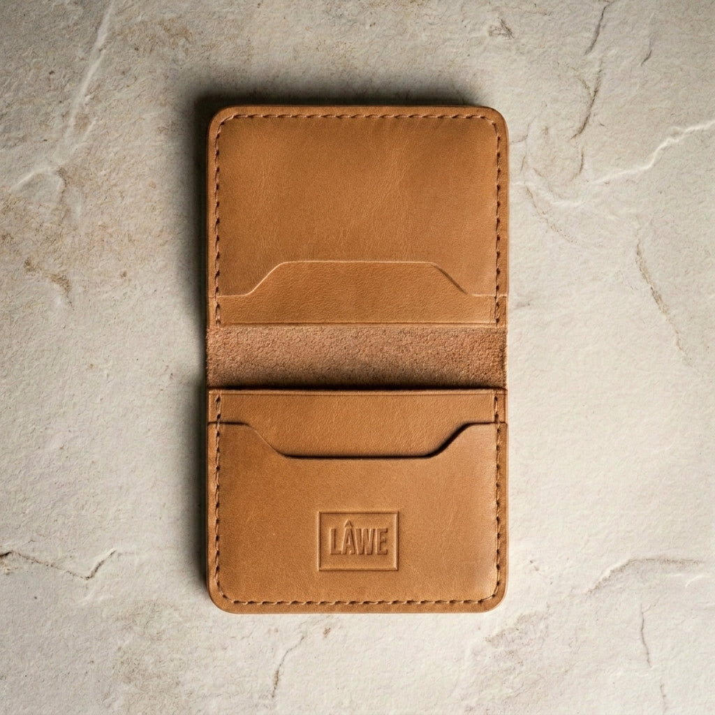 Light brown leather wallet with 'LÅWE' branding on a light stone surface