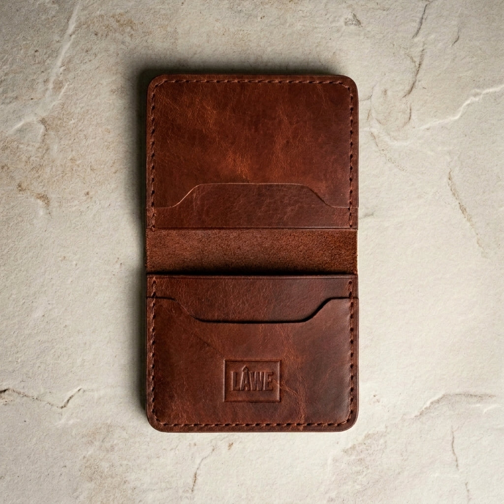 Red brown leather wallet with 'LÅWE' branding on a textured beige surface