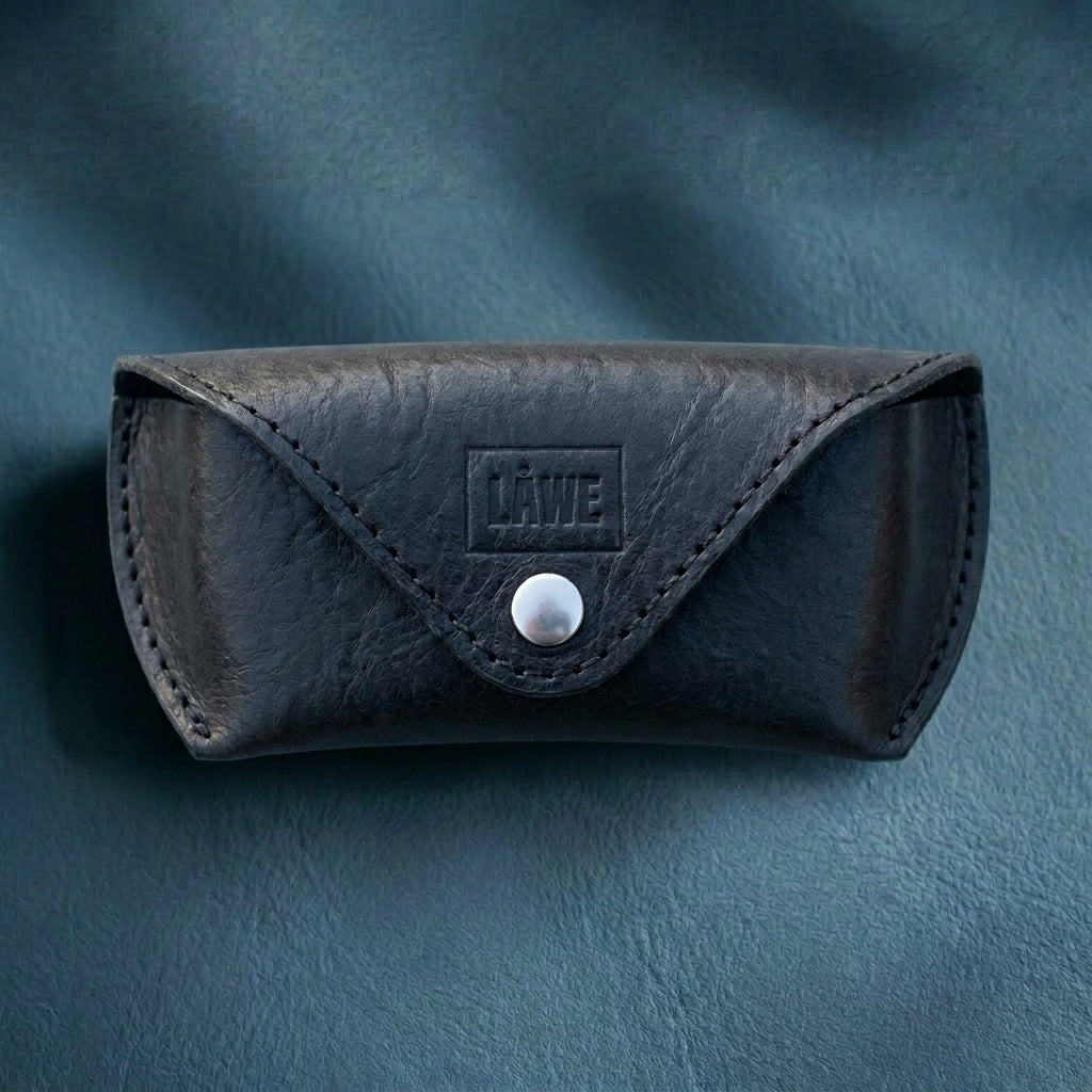 Black leather eyewear case with a metal button on a blue background