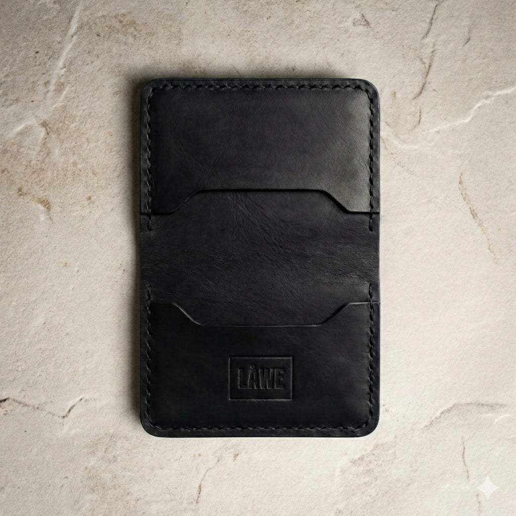 Black leather wallet with 'LAWE' branding on a beige stone surface