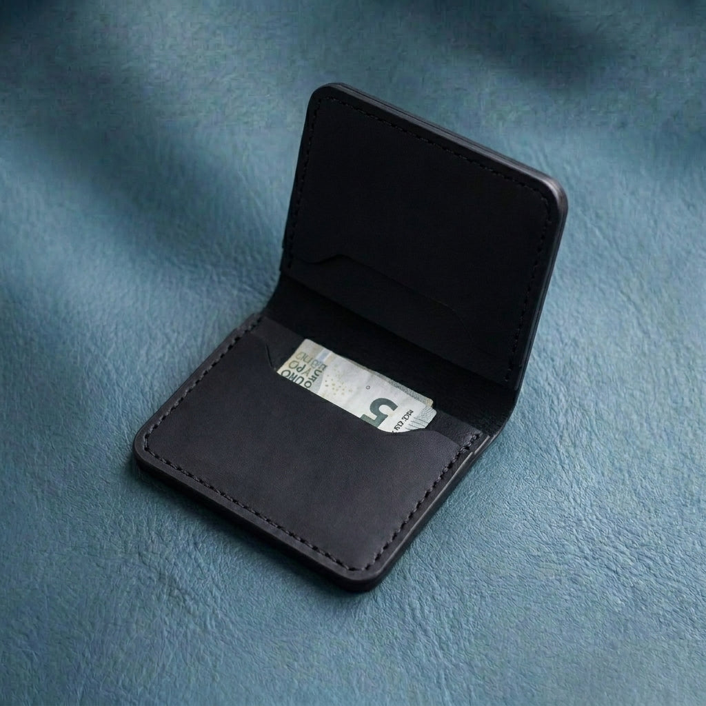 LÅWE Onyx Edge - black leather wallet with a banknote on a blue textured background