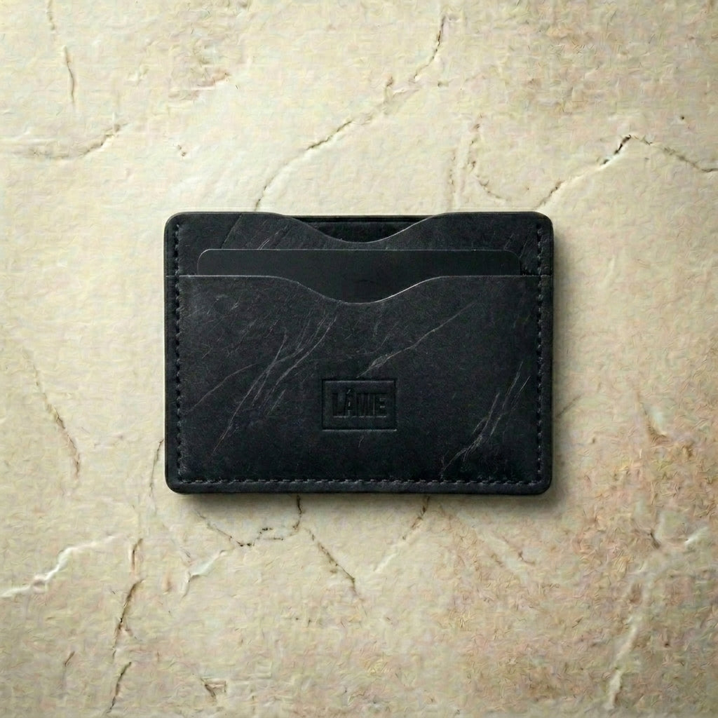 Black leather cardholder on a beige marble background