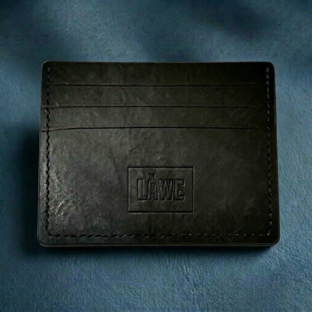 Black leather cardholder with 'LÅWE' branding on a blue textured background