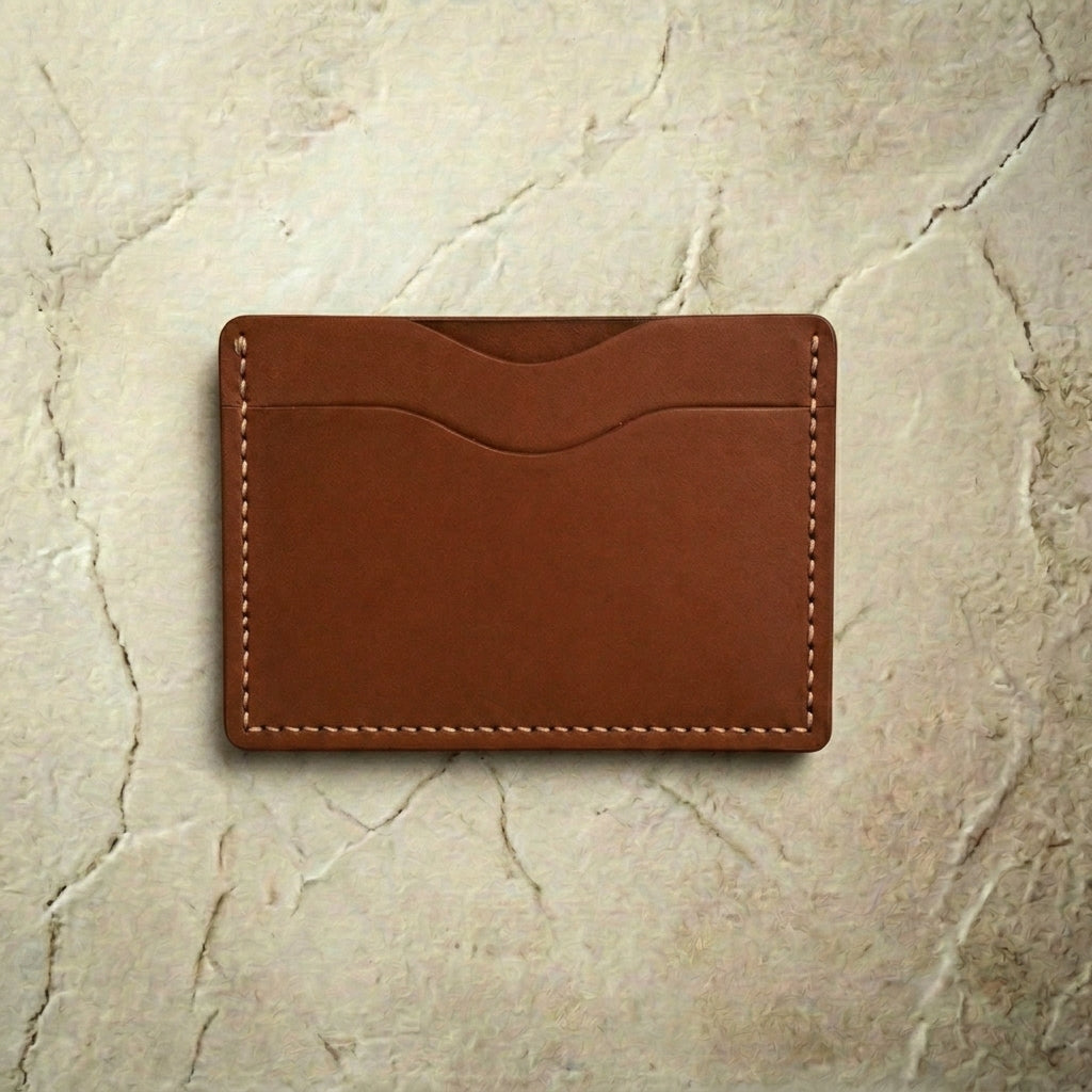 Brown leather cardholder on a textured beige surface