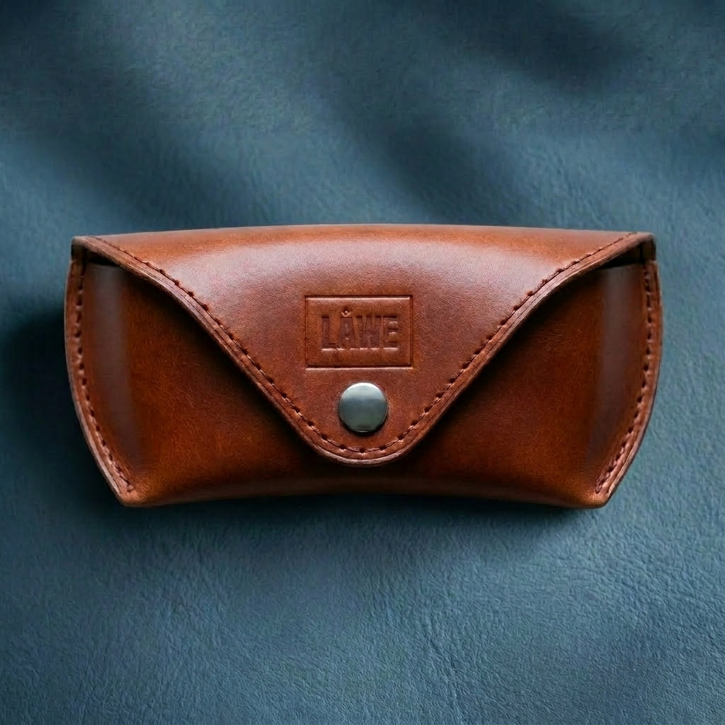 Brown leather eyewear case with a metal button on a blue background
