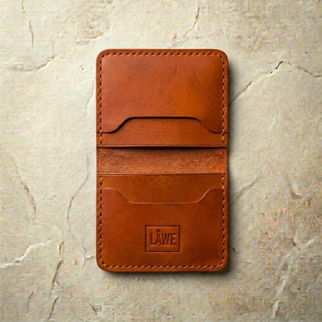 LÅWE Classic Rust Edge - medium brown leather wallet with branding on a beige stone background