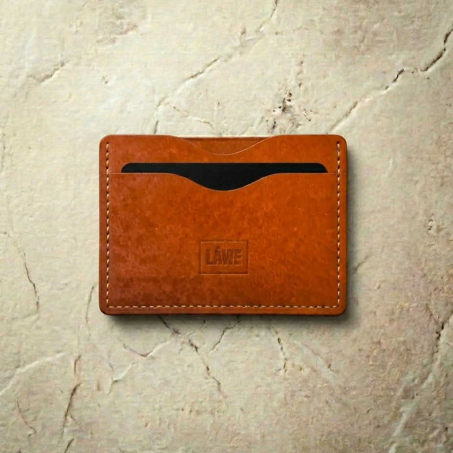 Orange leather cardholder with 'LÅWE' branding on a beige textured background