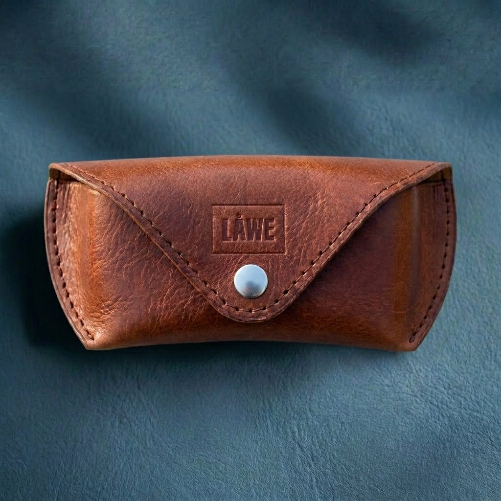 Brown leather eyewear case with a metal button on a blue background