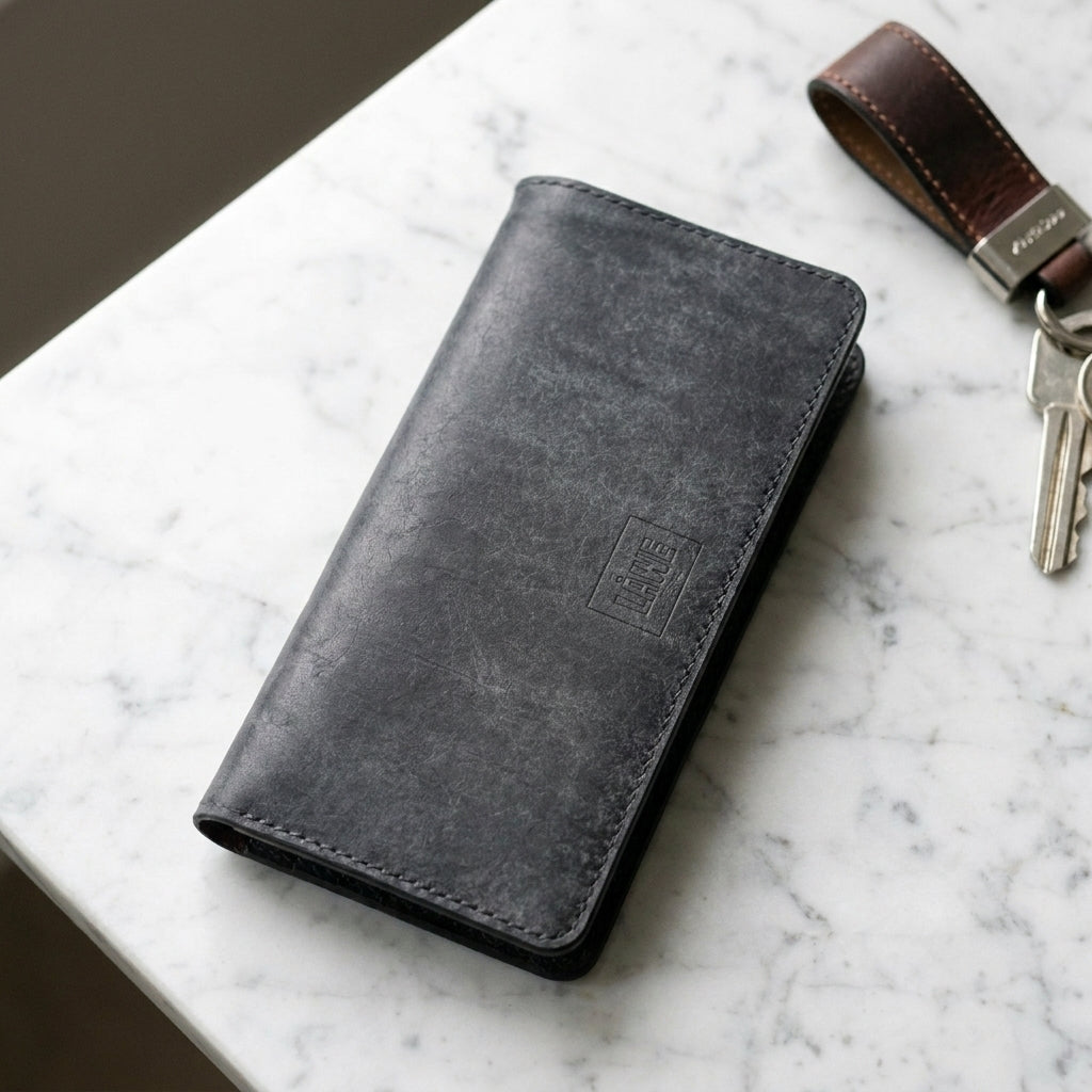 Slate blue leather wallet and keys on a marble surface