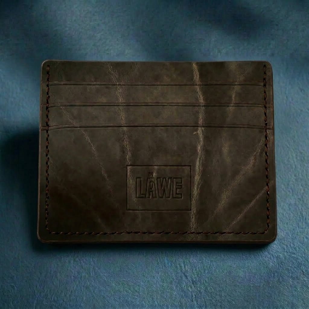 Grey leather cardholder with 'LÅWE' branding on a blue textured background