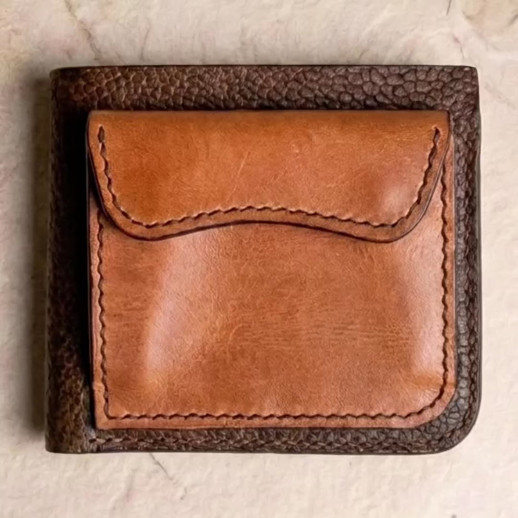 LÅWE Cove wallet in textured dark brown leather with a curved cognac snap pocket. Gloved hands open the pocket and unfold the wallet, revealing navy card slots and contrasting tan leather. Close-ups show the stitching, followed by an in-hand view and the wallet beside pour-over coffee. The Reel ends with the LÅWE logo and “Crafted to Carry You”.